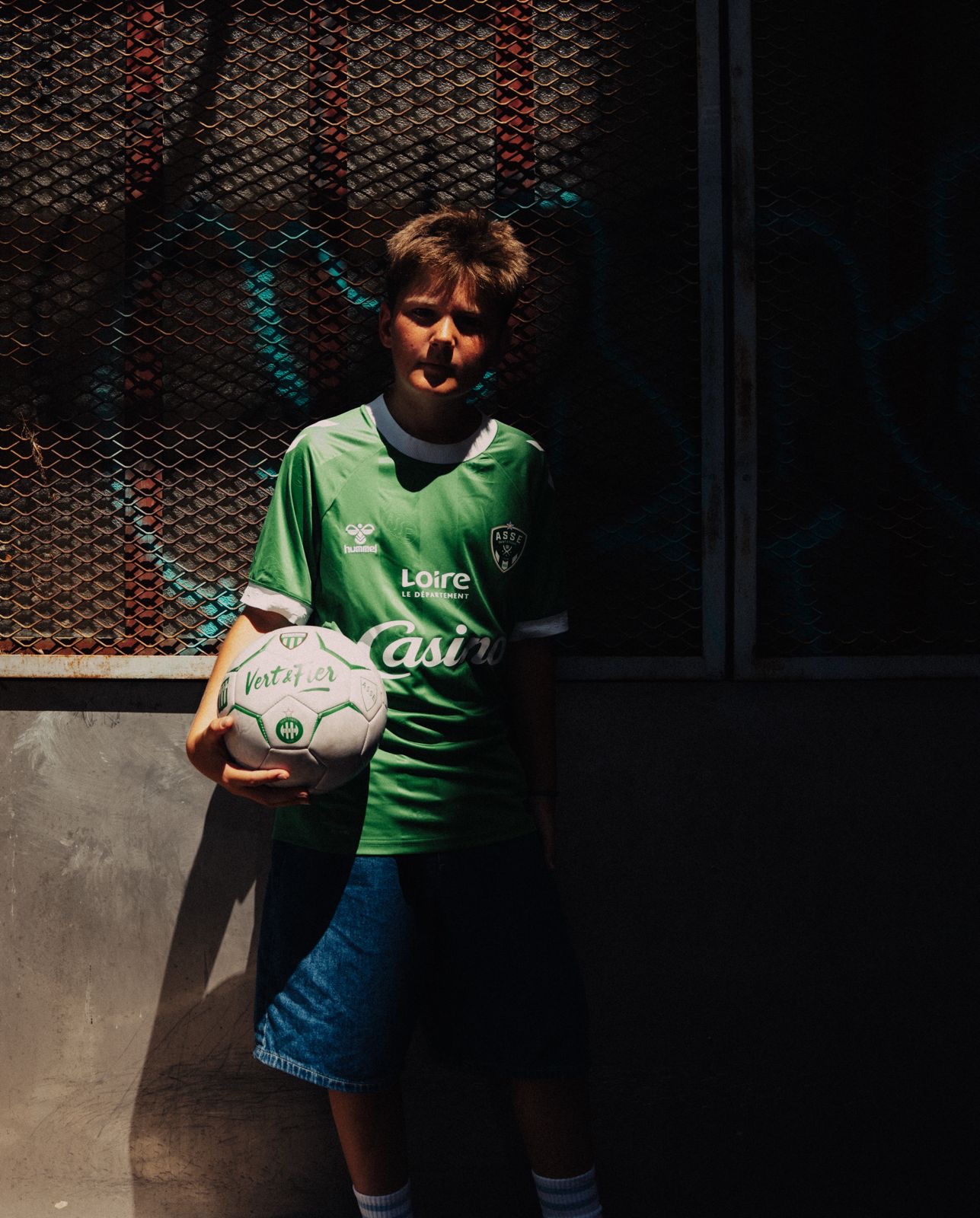Child with a ball, wearing the ASSE x Hummel jersey